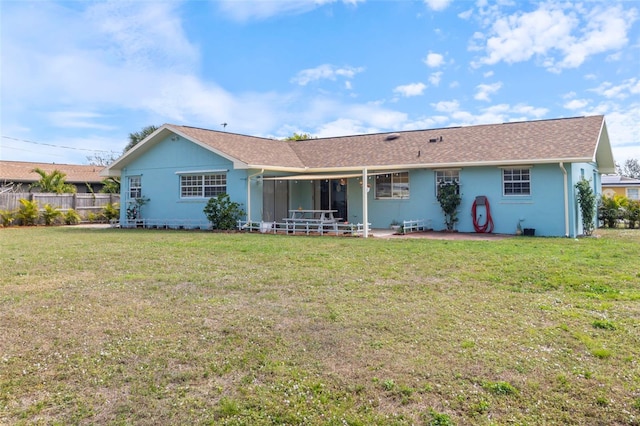 rear view of property with fence and a lawn