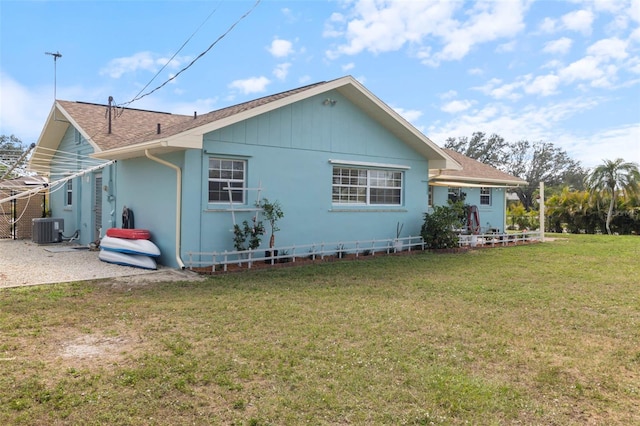 rear view of property with a lawn and central air condition unit