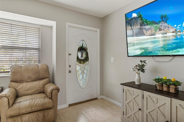 foyer entrance with plenty of natural light, baseboards, a textured ceiling, and light tile patterned flooring