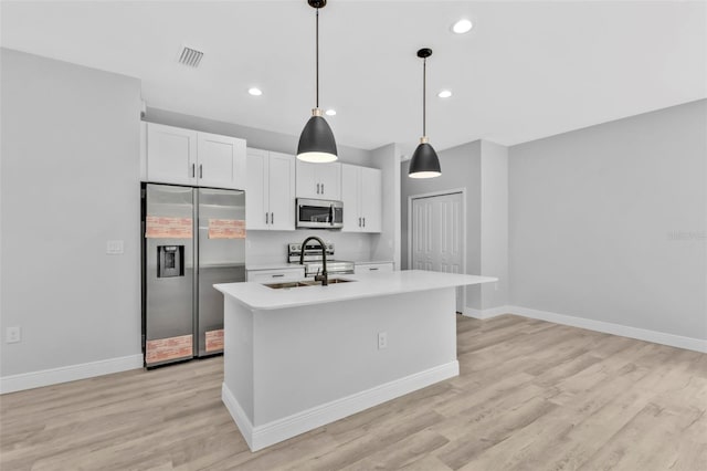 kitchen featuring stainless steel appliances, an island with sink, sink, and white cabinetry