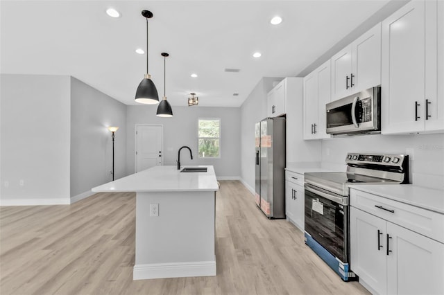 kitchen featuring pendant lighting, appliances with stainless steel finishes, sink, and white cabinets