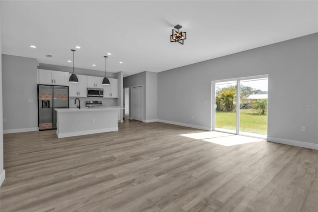 unfurnished living room with sink and light wood-type flooring