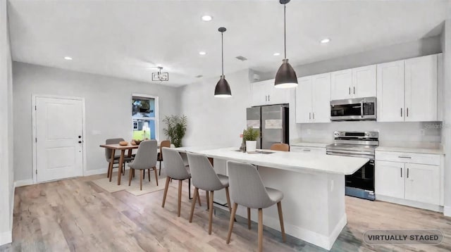 kitchen with white cabinetry, stainless steel appliances, and a kitchen island with sink