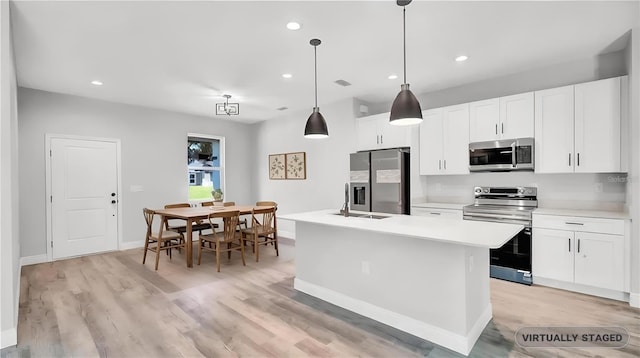 kitchen with appliances with stainless steel finishes, a kitchen island with sink, and white cabinets