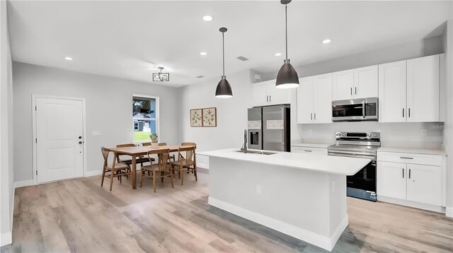 kitchen featuring a kitchen island with sink, white cabinetry, and stainless steel appliances