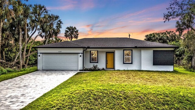 1117 Vernon Ave, Port Charlotte, FL 33948 - view of front facade with an attached garage, stucco siding, decorative driveway, and a front yard