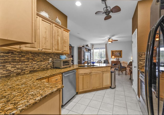 kitchen featuring sink, stone countertops, light tile patterned floors, appliances with stainless steel finishes, and backsplash