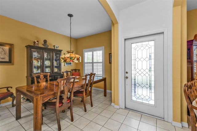 dining room featuring light tile patterned floors, arched walkways, and baseboards