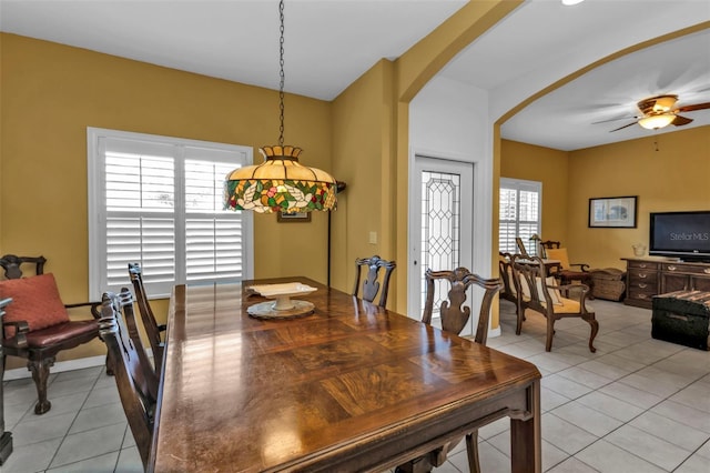 dining room with light tile patterned floors, arched walkways, and ceiling fan