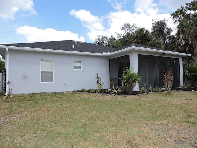 rear view of property featuring a lawn, stucco siding, a sunroom, and roof with shingles