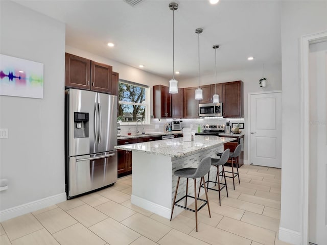 kitchen featuring sink, a breakfast bar, stainless steel appliances, tasteful backsplash, and a kitchen island