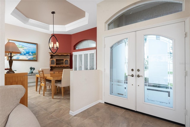 entryway with french doors, crown molding, a baseboard radiator, a tray ceiling, and a notable chandelier