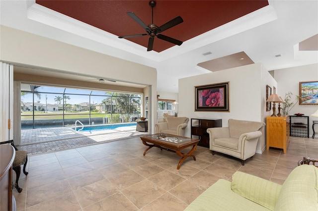 living room featuring ornamental molding, ceiling fan, and a tray ceiling