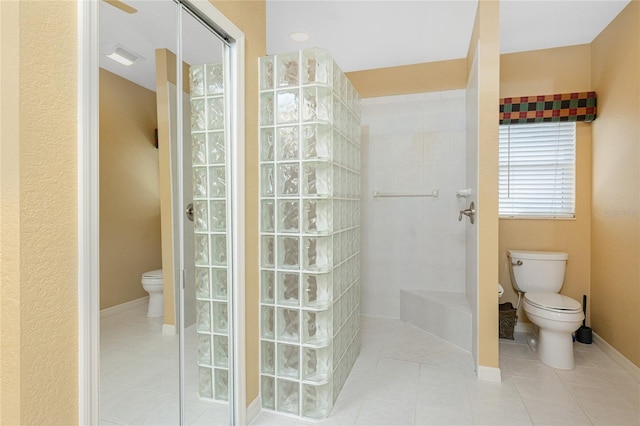 bathroom featuring tile patterned flooring, toilet, and tiled shower