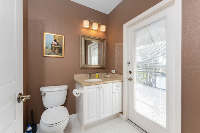 bathroom with vanity, toilet, tile patterned flooring, and a wealth of natural light