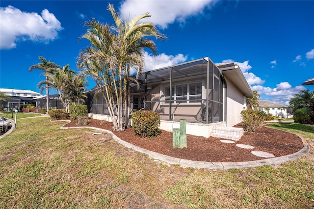 view of side of property with a yard and glass enclosure