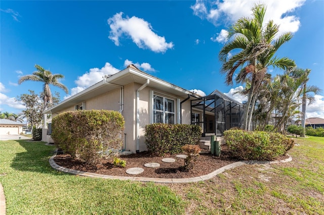 view of side of property with a lanai and a yard