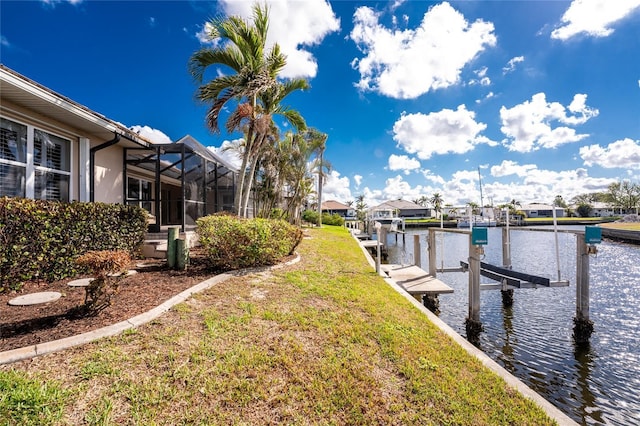 dock area with a water view, glass enclosure, and a lawn