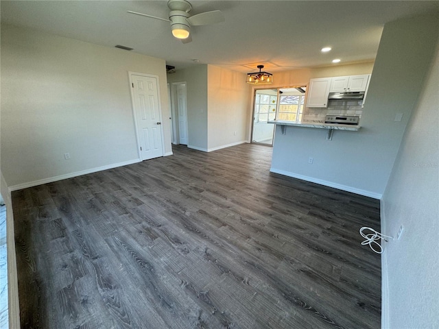 kitchen with stainless steel electric range oven, a breakfast bar, white cabinets, decorative backsplash, and dark wood-type flooring