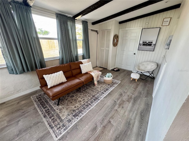 living room with beamed ceiling, wood-type flooring, and wood walls