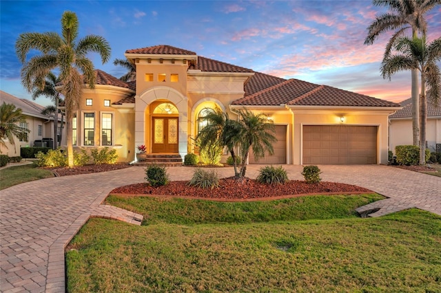 mediterranean / spanish home with a garage, central AC, a lawn, and french doors