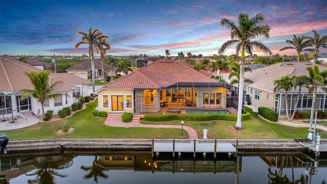 3321 Tripoli Blvd, Punta Gorda, FL 33950 - back house at dusk with a water view, a patio, glass enclosure, and a lawn