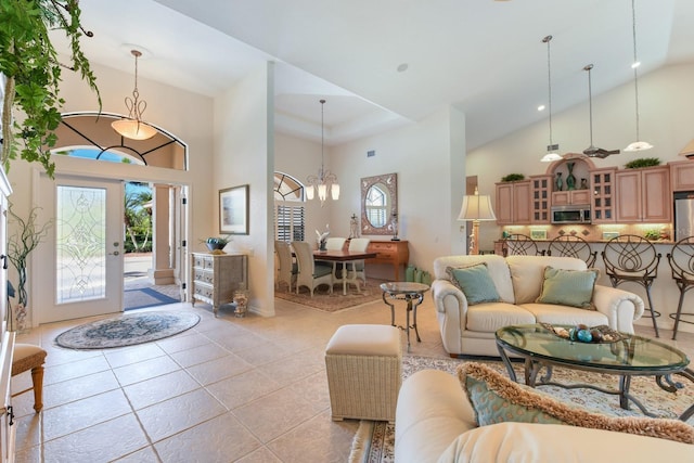 living room with light tile patterned flooring, a notable chandelier, high vaulted ceiling, and a wealth of natural light