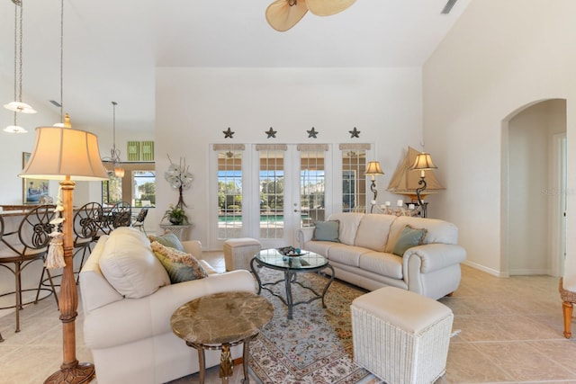 tiled living room with french doors, ceiling fan, and a high ceiling