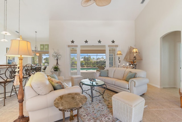 living room with a towering ceiling, light tile patterned floors, and ceiling fan