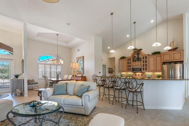 living room with a chandelier, a raised ceiling, a high ceiling, and light tile patterned floors