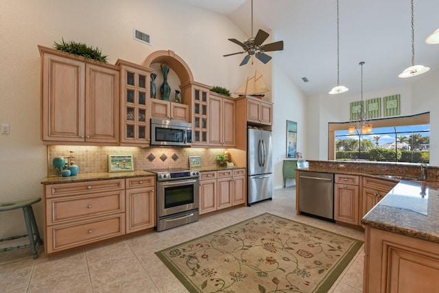 kitchen featuring appliances with stainless steel finishes, decorative light fixtures, dark stone countertops, backsplash, and ceiling fan