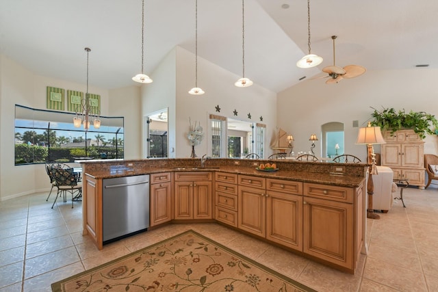 kitchen featuring dishwasher, high vaulted ceiling, a center island with sink, decorative light fixtures, and dark stone counters