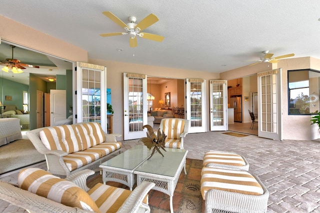 living room with a textured ceiling, french doors, and ceiling fan