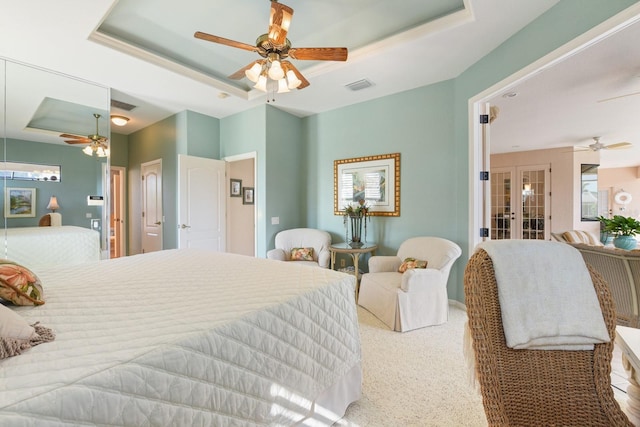 bedroom featuring a raised ceiling, ceiling fan, and french doors