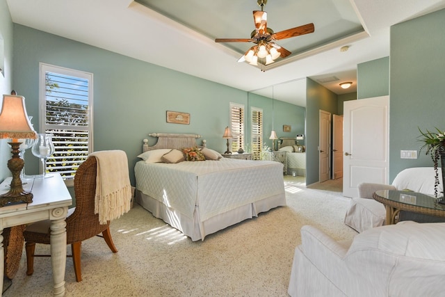 carpeted bedroom with a tray ceiling and ceiling fan