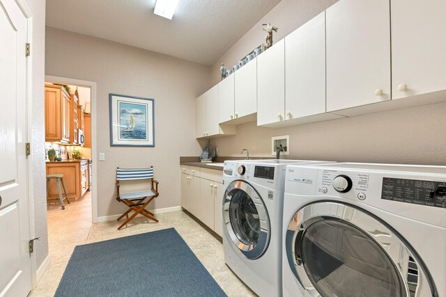 clothes washing area with separate washer and dryer, sink, cabinets, light tile patterned floors, and a textured ceiling