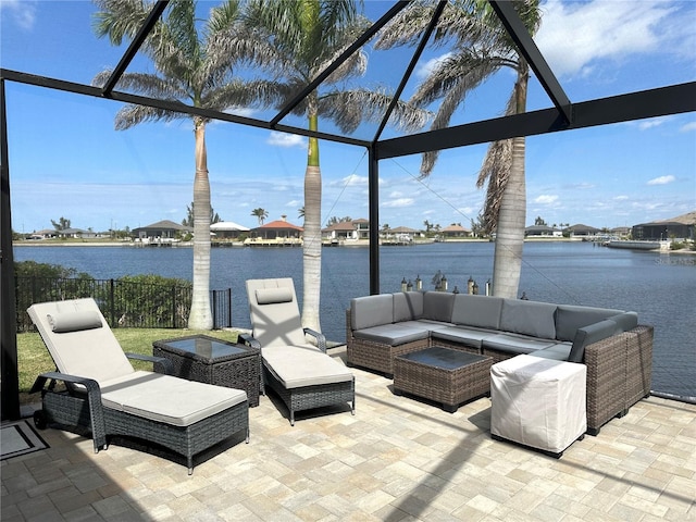 view of patio featuring glass enclosure, outdoor lounge area, fence, and a water view