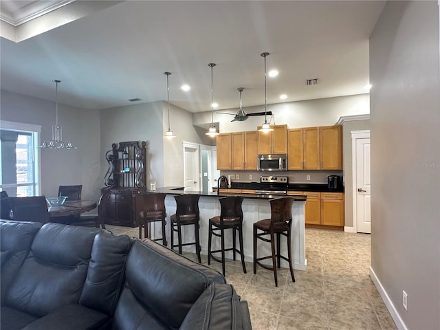 kitchen with appliances with stainless steel finishes, dark countertops, open floor plan, and a kitchen breakfast bar