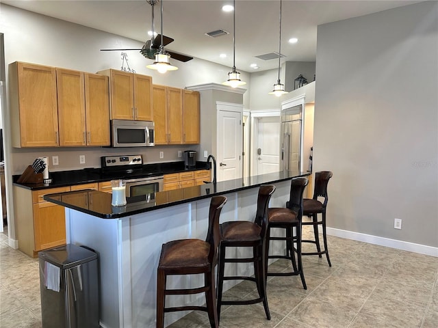 kitchen with stainless steel appliances, baseboards, visible vents, and a kitchen bar