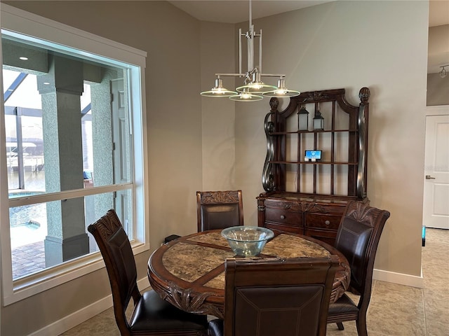 dining space featuring a healthy amount of sunlight, a notable chandelier, and baseboards