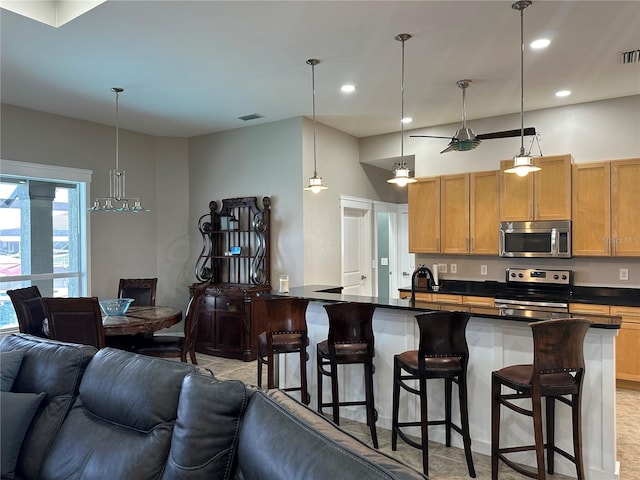 kitchen with visible vents, dark countertops, a breakfast bar, open floor plan, and stainless steel appliances