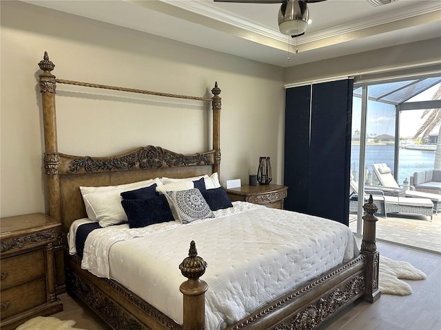 bedroom with access to exterior, a water view, ornamental molding, a sunroom, and wood finished floors