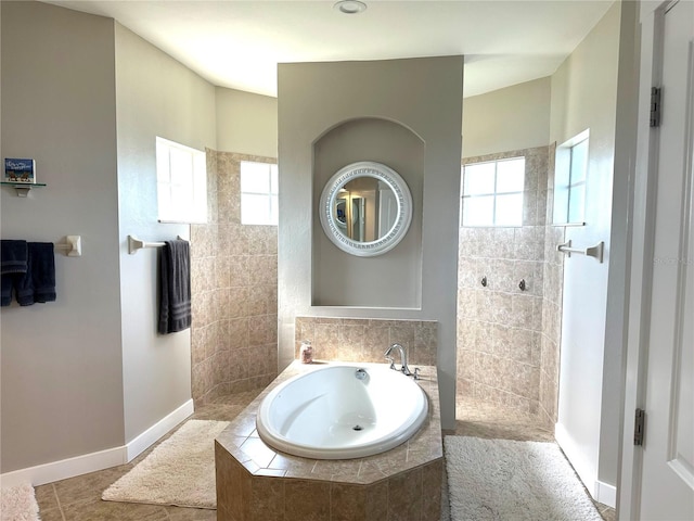 bathroom featuring baseboards, walk in shower, a bath, and tile patterned floors