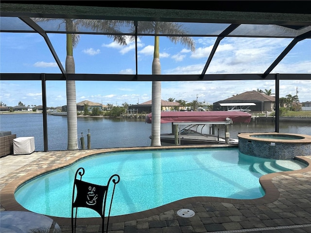 view of pool featuring a water view, glass enclosure, a pool with connected hot tub, and a patio area