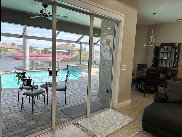 doorway featuring a water view, tile patterned flooring, baseboards, and a ceiling fan