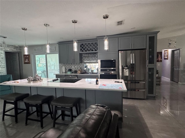 kitchen featuring stainless steel appliances, a spacious island, decorative backsplash, and decorative light fixtures