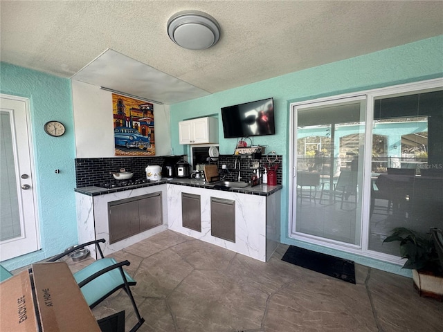 kitchen featuring backsplash, a textured ceiling, sink, and white cabinets