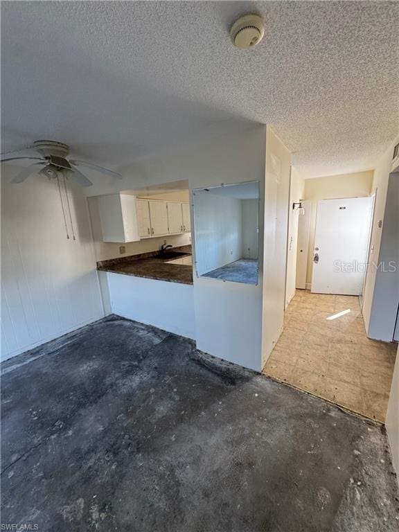 kitchen with ceiling fan, a textured ceiling, and concrete floors