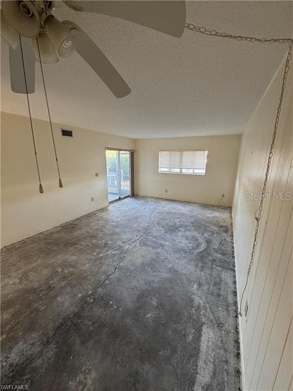 empty room with ceiling fan and a textured ceiling