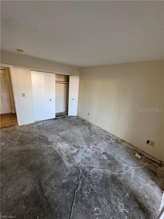 unfurnished bedroom with concrete floors and a closet